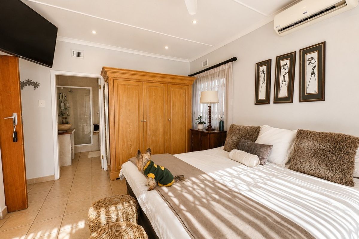 Spacious bedroom featuring tiled flooring, a ceiling fan, split-system air conditioning, and an adjoining en-suite bathroom.
