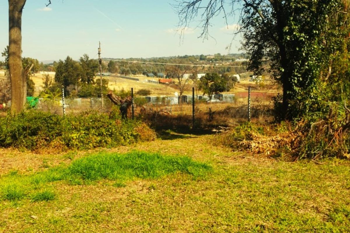 A view of the surrounding farm landscape and open fields, featuring established trees and perimeter fencing.
