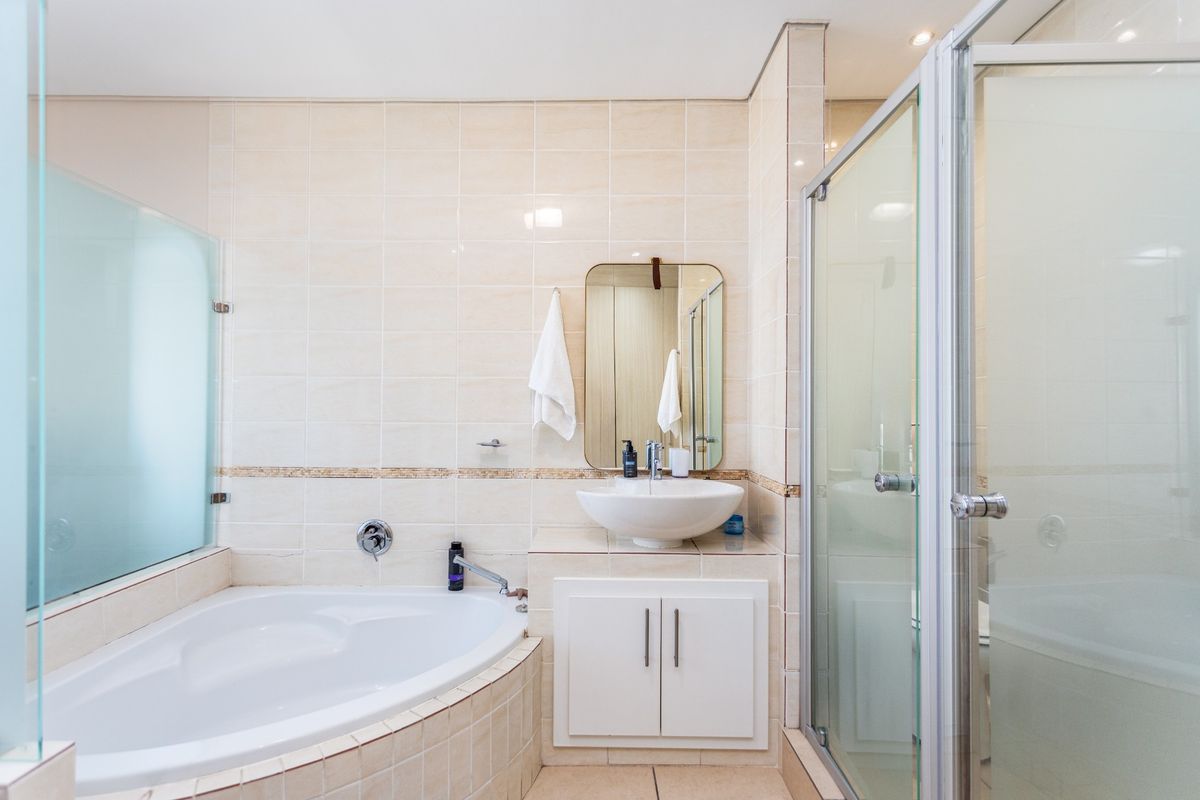 A functional bathroom featuring a corner bathtub, a separate glass-enclosed shower, and a vanity basin with built-in cabinetry.