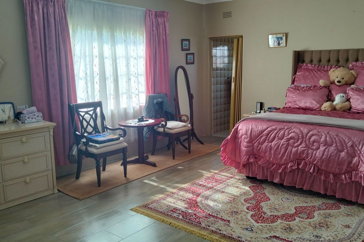 A spacious bedroom featuring tiled flooring, large windows with natural light, and an en-suite bathroom access point.