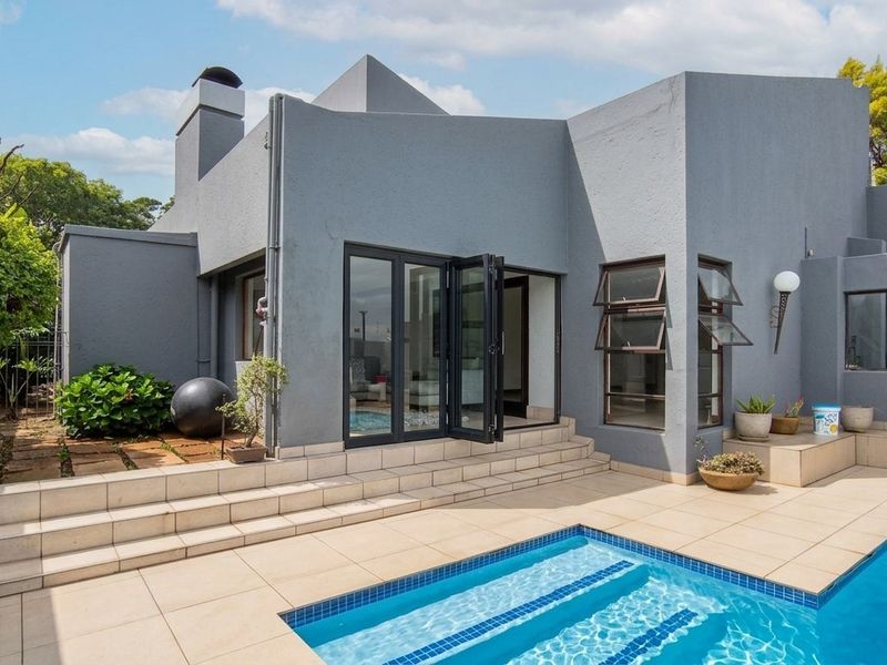 Rear exterior view featuring a modern swimming pool, tiled patio area, and bi-fold doors leading into the home.