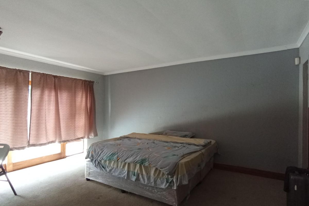 A spacious bedroom featuring carpeted flooring, coving, and a large sliding glass door providing natural light.