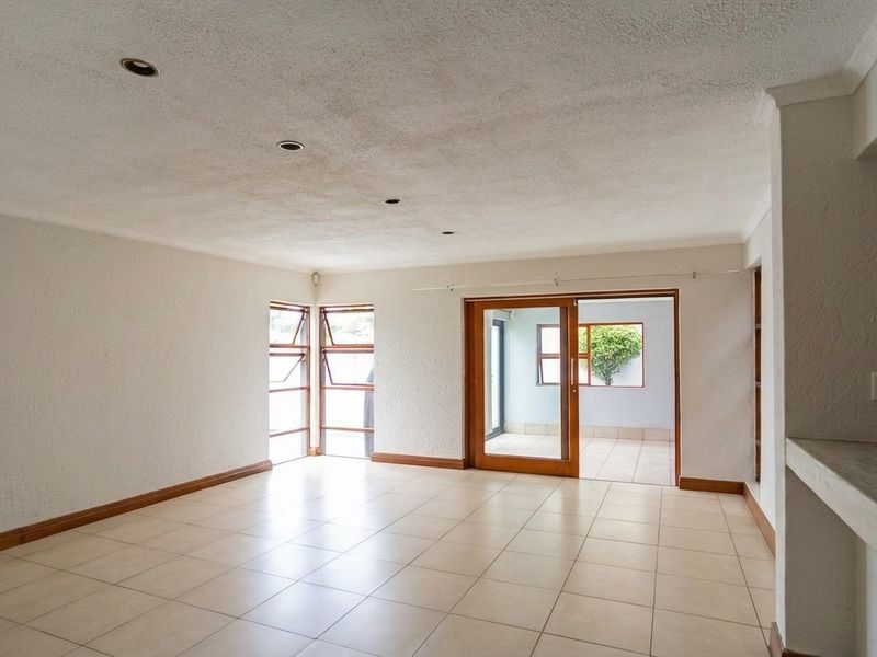 Spacious, empty living area featuring tiled floors, recessed lighting, and a sliding glass door leading to an outdoor patio space.