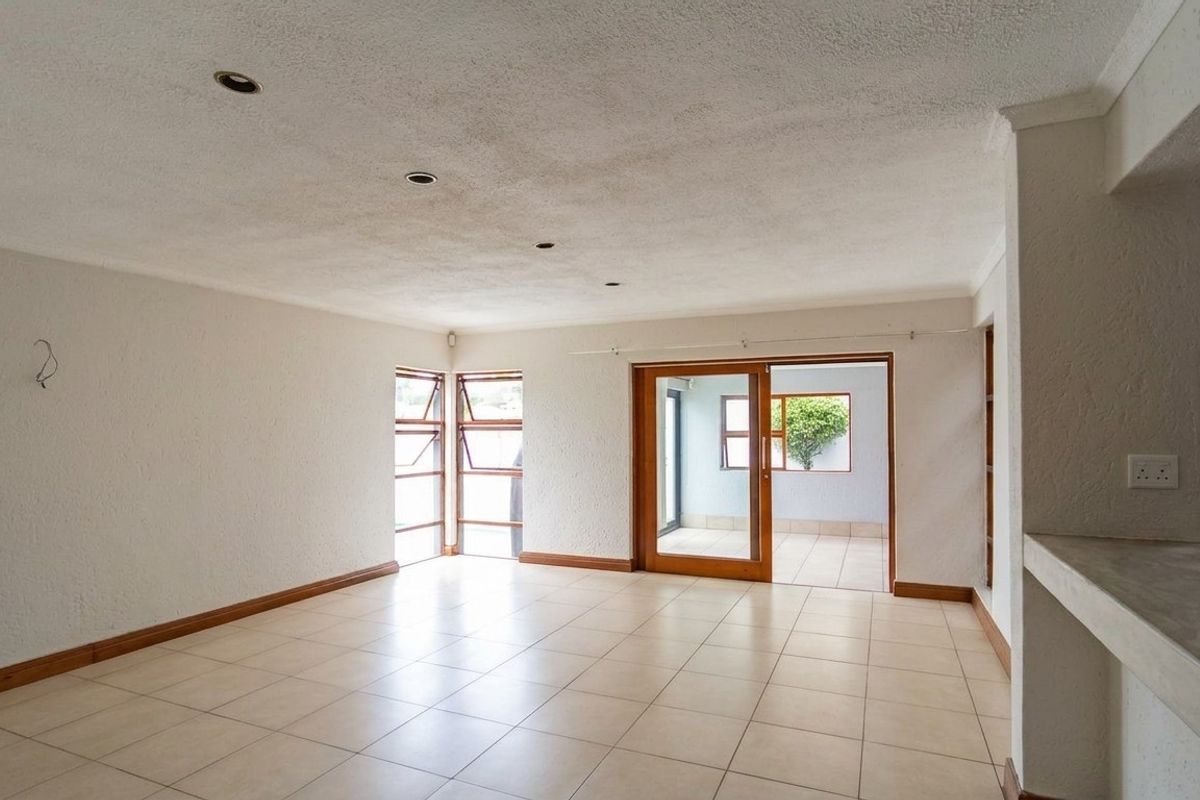 Spacious, empty living area featuring tiled floors, recessed lighting, and a sliding glass door leading to an outdoor patio space.