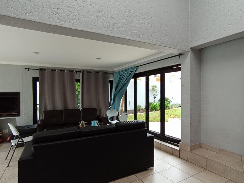 Spacious living area featuring a built-in fireplace, tiled flooring, and large sliding glass doors providing direct access to the garden.