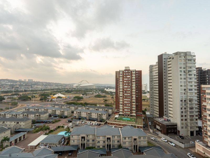 Elevated urban view overlooking surrounding apartment complexes, residential streets, and distant city landmarks under a cloudy sky.
