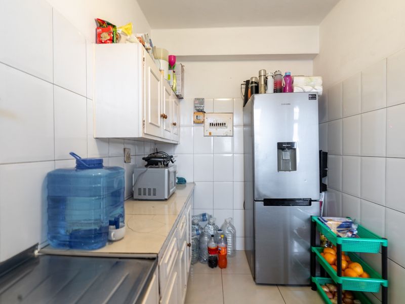 A compact scullery or utility area featuring tiled walls, built-in cabinetry, and an electrical distribution board, providing functional storage and utility space.