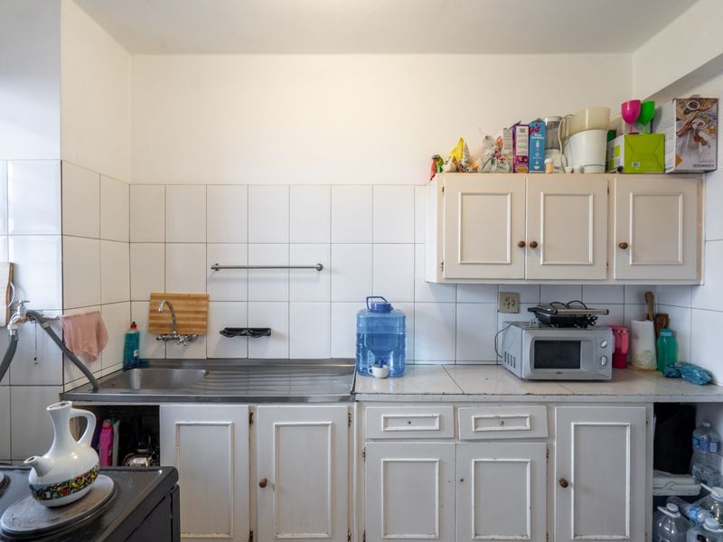 A functional kitchen area featuring white cabinetry, a stainless steel sink, and a tiled backsplash, offering a practical layout for daily use.