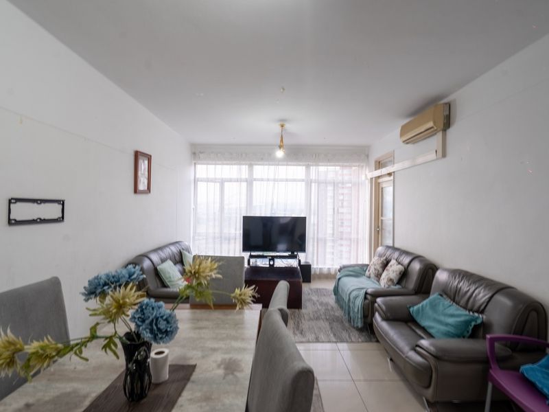 Open-plan living and dining area featuring tiled flooring, large windows providing natural light, and a wall-mounted split-system air conditioner.