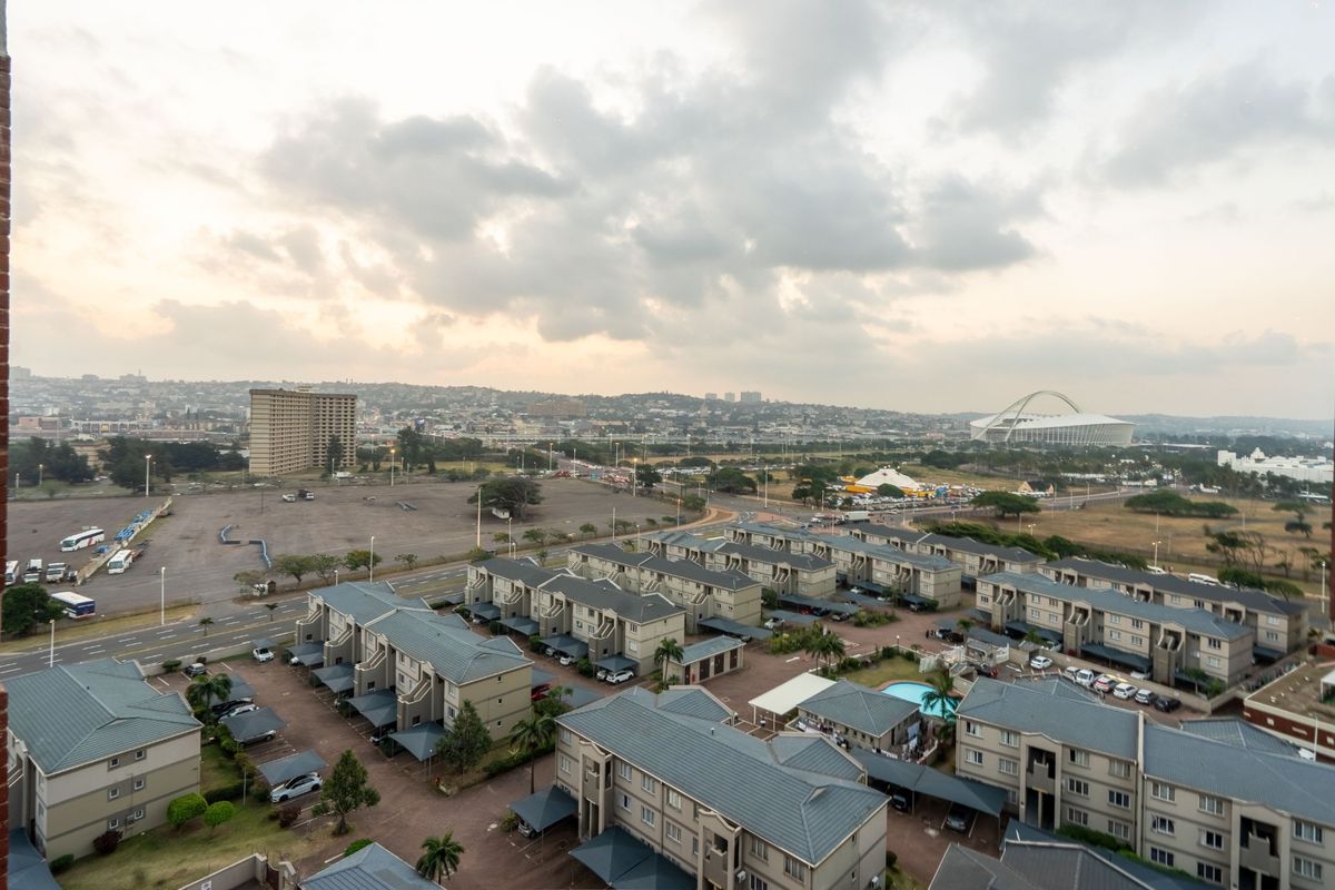 An elevated aerial view of a residential apartment complex featuring multiple buildings, covered parking carports, and a communal swimming pool.