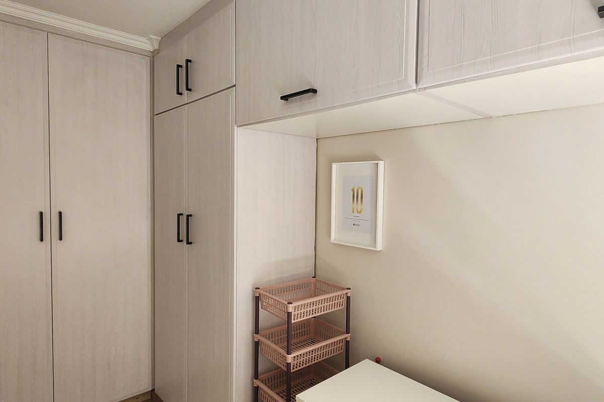 A bedroom featuring light-toned built-in cupboards and overhead storage cabinets, providing ample integrated storage space.