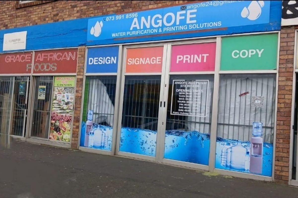 Commercial storefront featuring large glass display windows with business signage and branding for water purification and printing services.