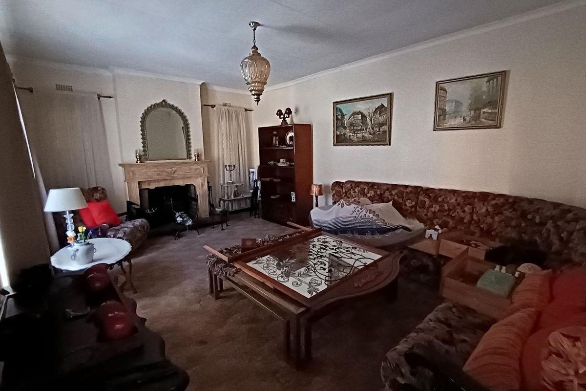 A traditional living room featuring a built-in fireplace, carpeted flooring, and classic architectural details, offering a cozy and dated aesthetic.