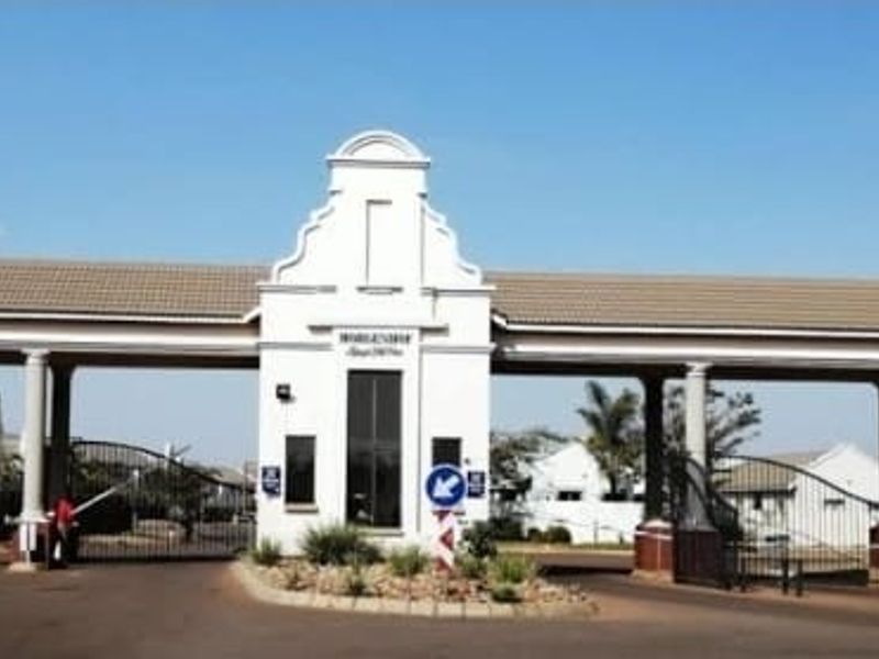 The main entrance gatehouse of the apartment complex, featuring a secure boom gate system and well-maintained architectural facade.