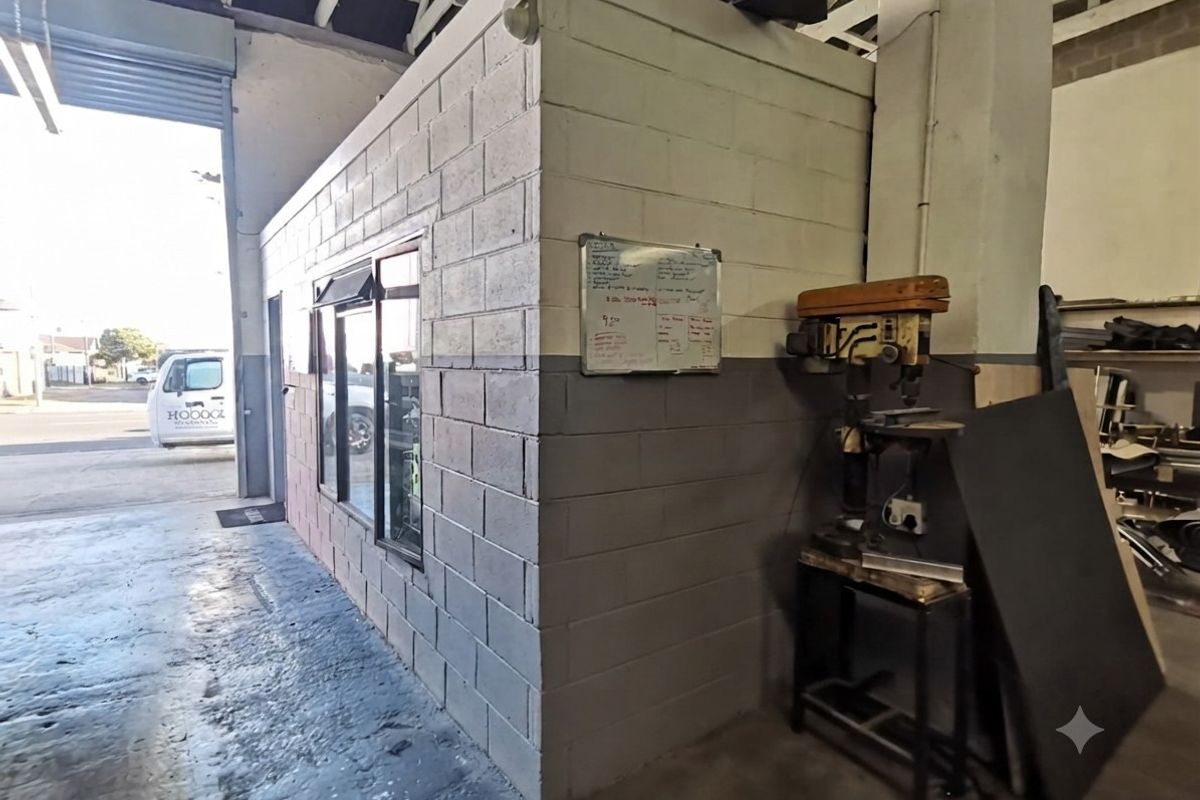 Industrial warehouse interior featuring a partitioned office structure with masonry walls, concrete flooring, and direct access to the exterior loading area.