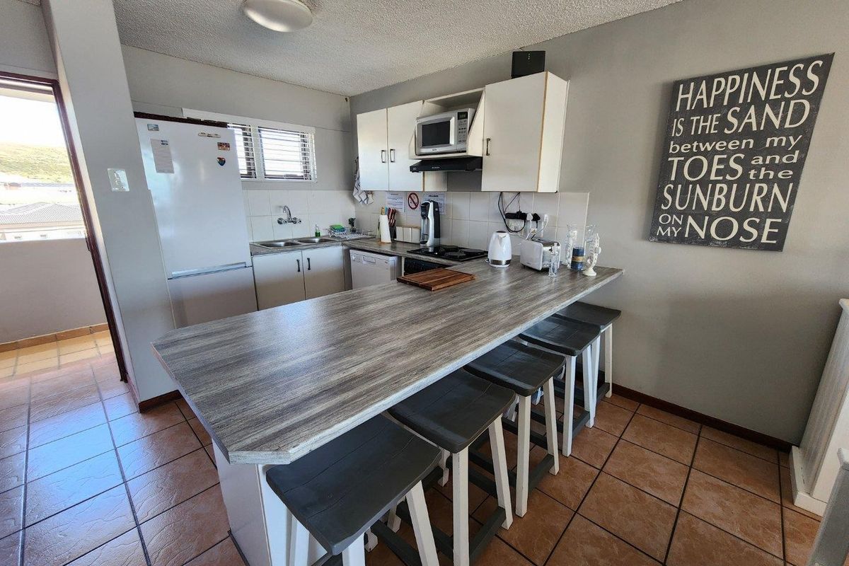 Compact kitchen featuring a breakfast bar, built-in cabinetry, tiled flooring, and integrated appliances, offering a functional layout for casual dining.