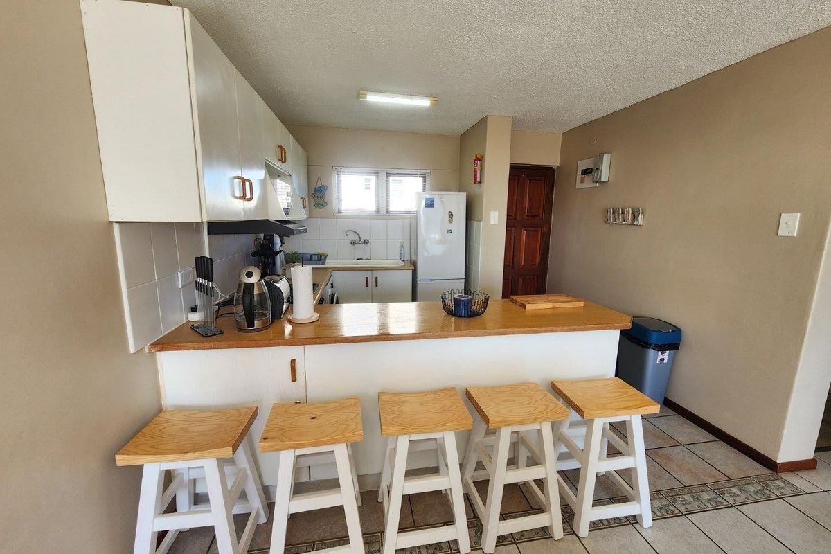 A functional kitchen featuring a breakfast bar, built-in cabinetry, tiled backsplash, and a double sink, offering a practical layout for daily use.
