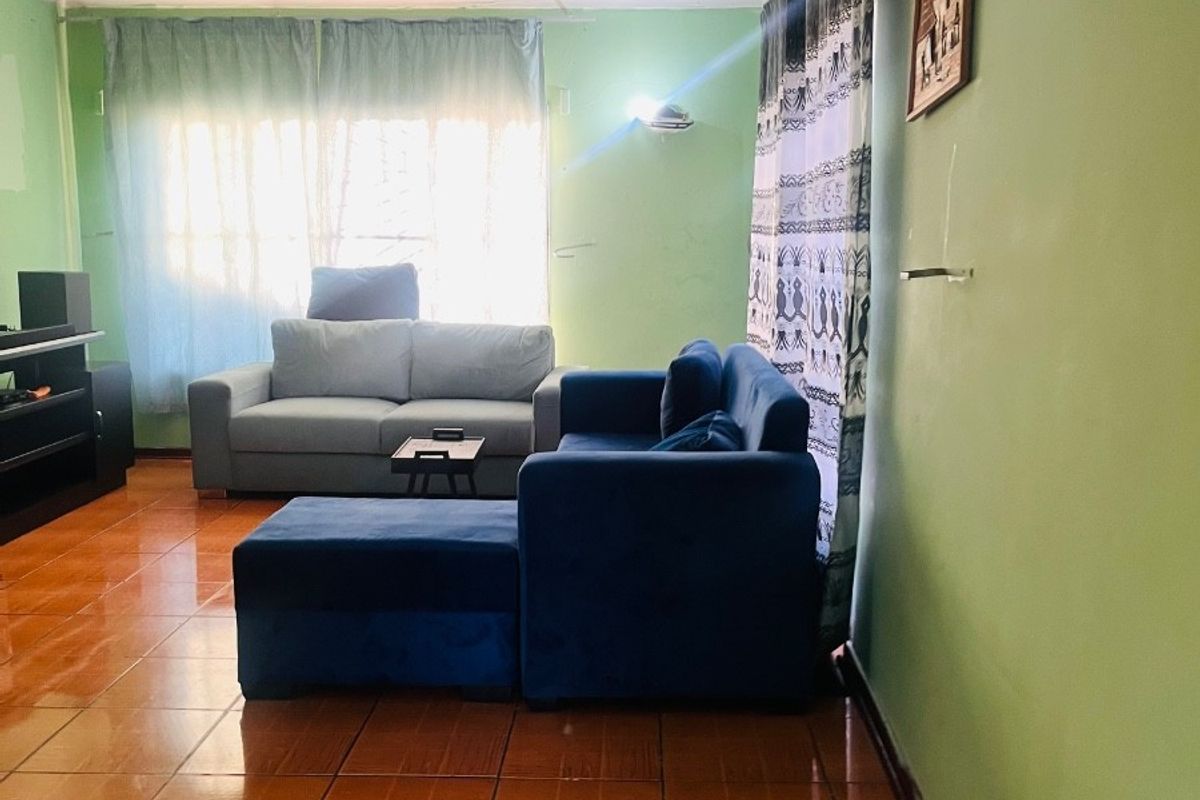 A living room featuring tiled flooring, green painted walls, and wall-mounted lighting fixtures.