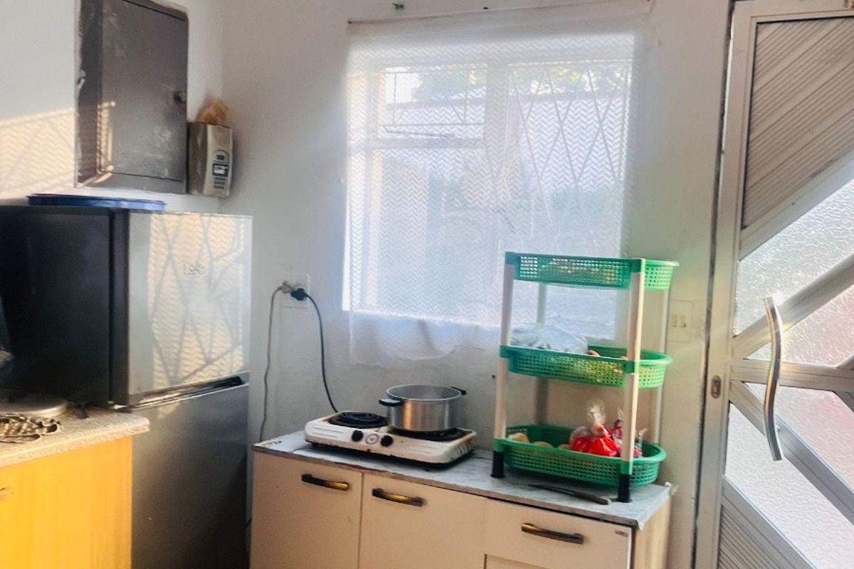 A compact kitchen area featuring basic cabinetry, tiled flooring, and a security door, providing a functional space for meal preparation.