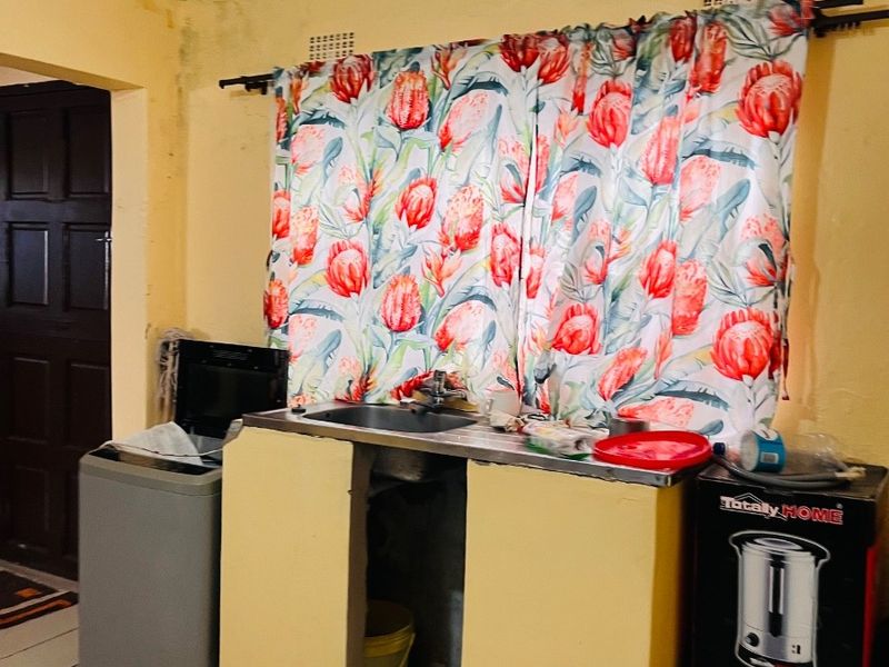 A functional laundry area featuring a stainless steel sink, tiled flooring, and ventilation bricks, currently requiring cosmetic updates and finishings.