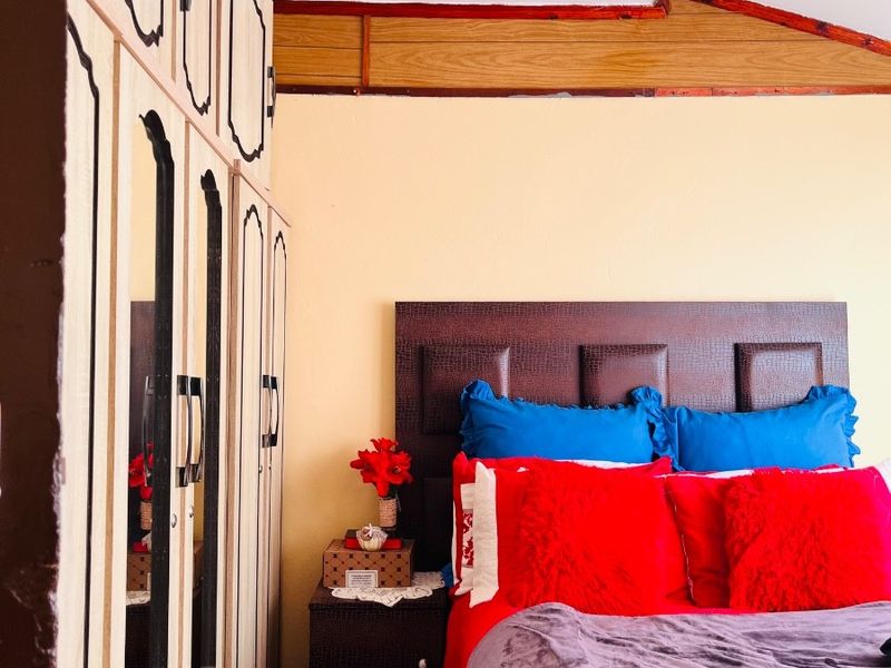Bedroom featuring built-in wardrobes and exposed timber ceiling beams, offering a functional space with potential for cosmetic updates.