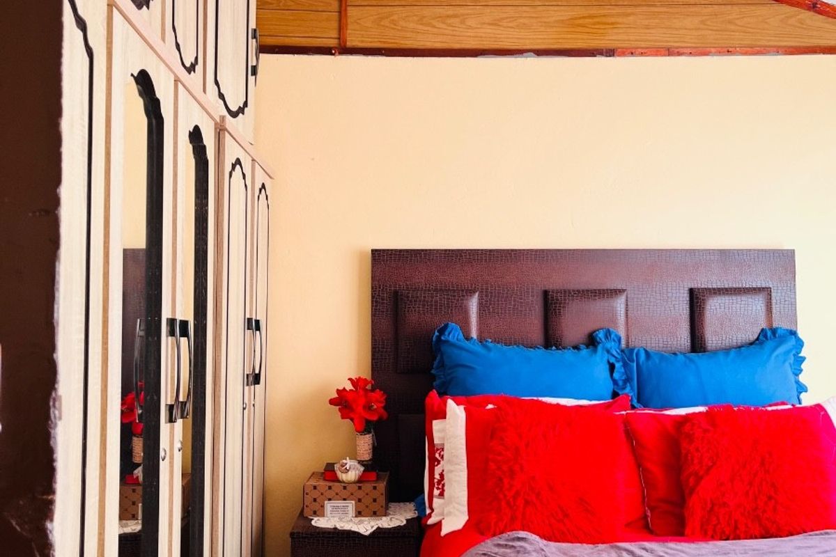 Bedroom featuring built-in wardrobes and exposed timber ceiling beams, offering a functional space with potential for cosmetic updates.