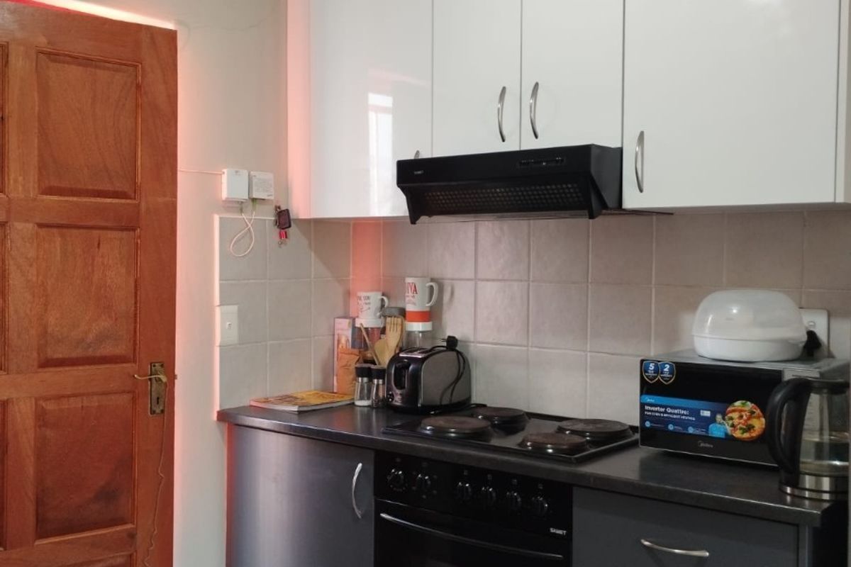 Compact kitchen featuring modern two-tone cabinetry, built-in oven, electric hob, and extractor fan with tiled splashback.