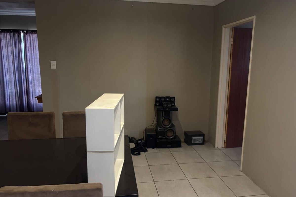 A view of a living area featuring tiled flooring, neutral wall tones, and a doorway leading to an adjacent room.