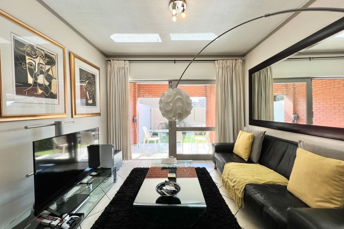 A well-lit living room featuring tiled flooring and large sliding glass doors that provide direct access to a private patio area.