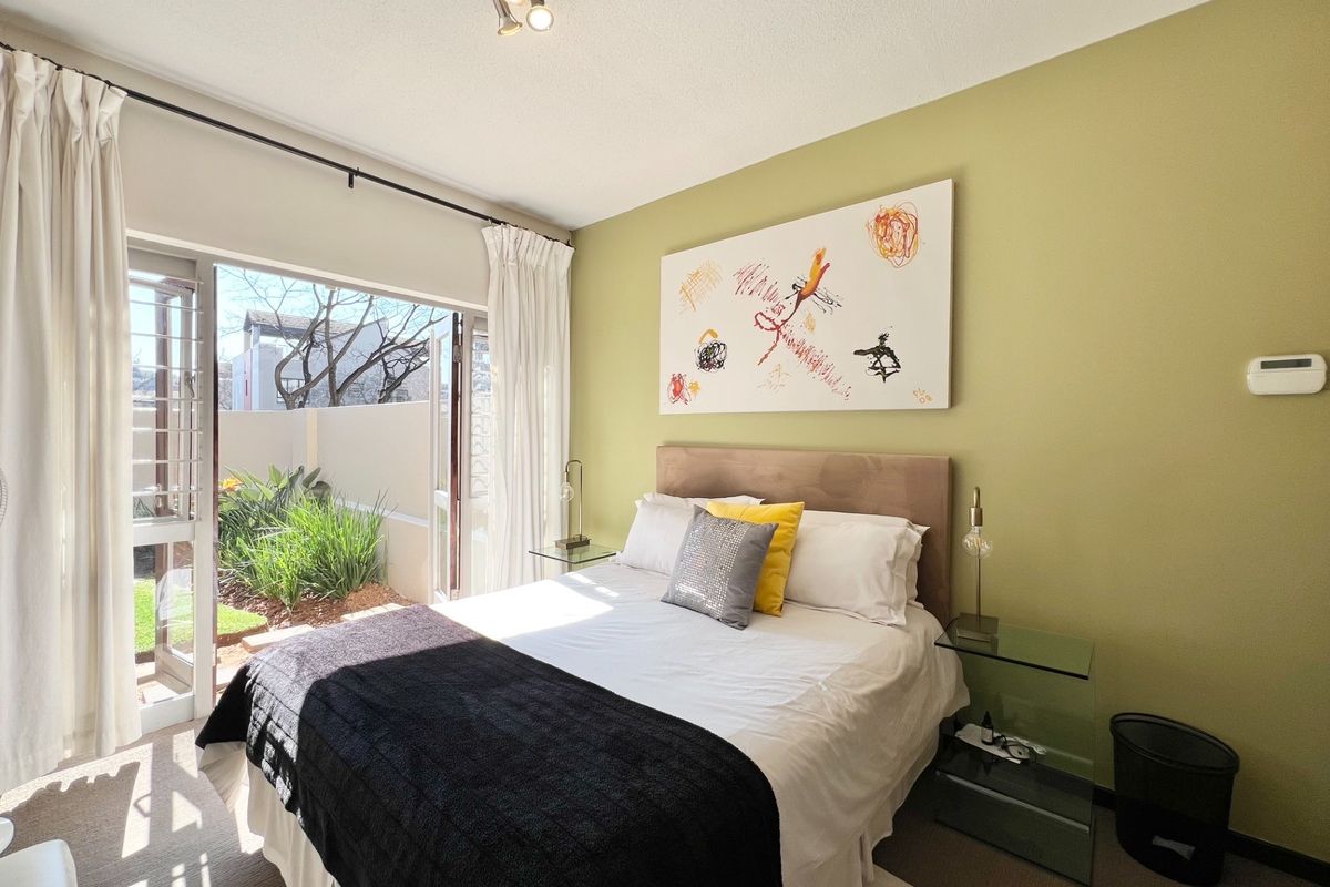 A bright bedroom featuring direct access to a private garden through glass sliding doors, creating a seamless indoor-outdoor living experience.