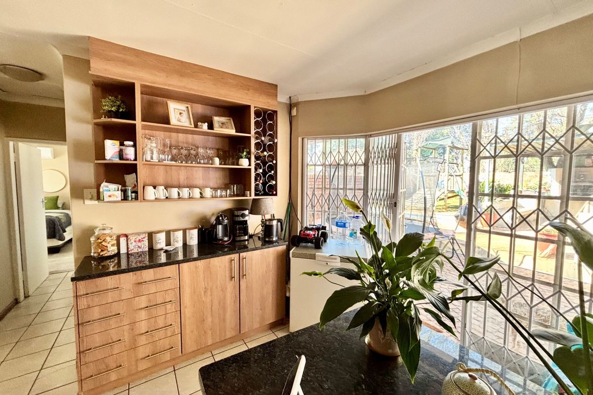 A functional kitchen area featuring light wood cabinetry, dark granite countertops, and built-in shelving with integrated wine storage, opening onto a patio area.