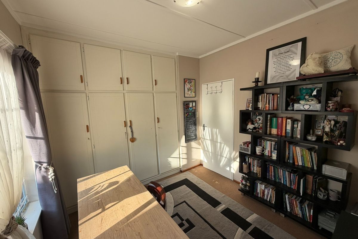 A bedroom featuring extensive built-in cupboard storage and carpeted flooring, offering a functional space with natural light.