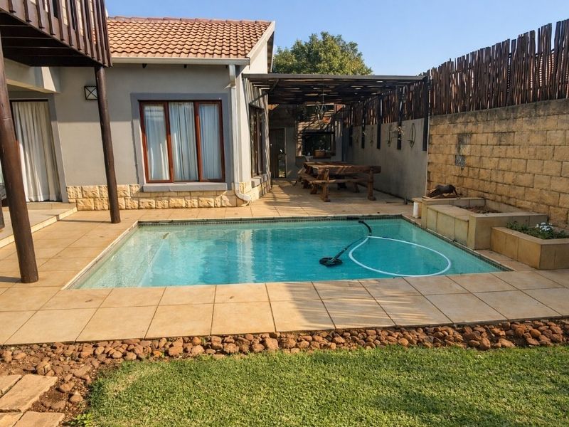 A well-maintained outdoor pool area featuring a tiled patio, pergola, and stone-clad boundary walls, providing a functional space for outdoor relaxation.