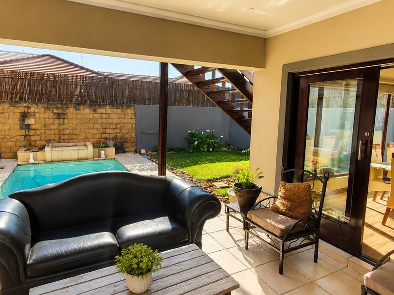 Covered patio area featuring tiled flooring and direct access to the swimming pool and garden, seamlessly connecting to the indoor living space.