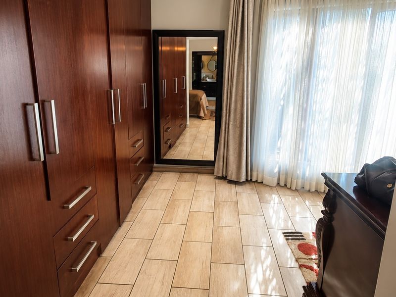A well-maintained bedroom featuring extensive built-in wooden cabinetry, tiled flooring, and large sliding glass doors that provide ample natural light.