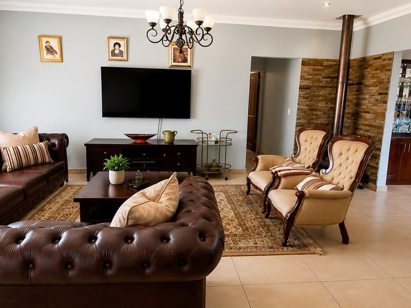 Spacious living room featuring a stone accent wall, a fireplace, and built-in cabinetry, finished with neutral floor tiles and elegant crown molding.