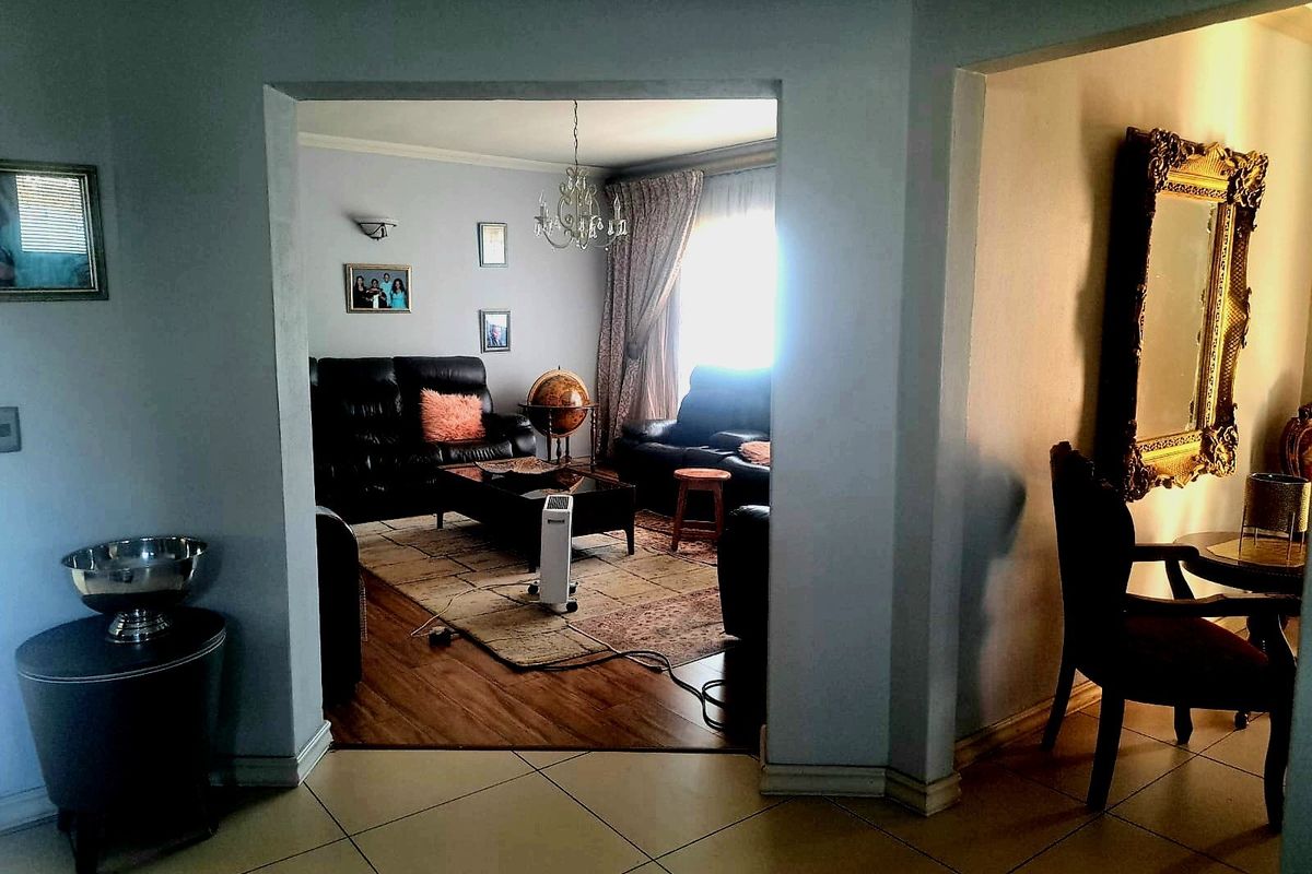 A view from a tiled hallway into a living room featuring laminate flooring and an arched entryway.