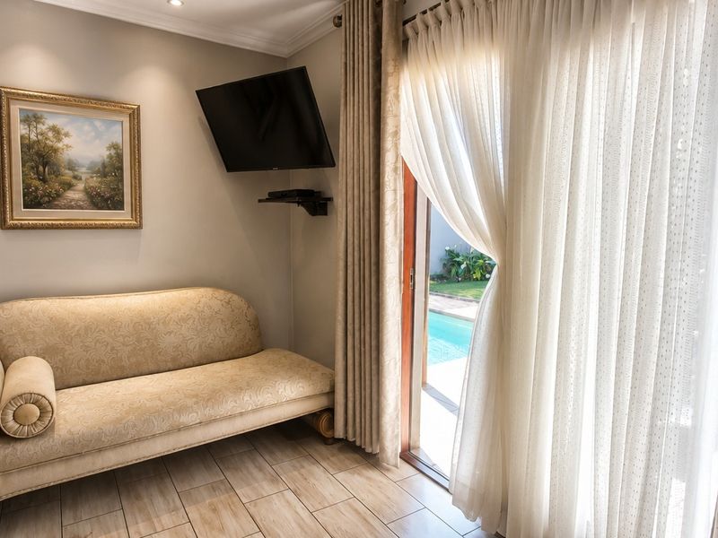 A well-maintained living area featuring tiled flooring, crown molding, and a sliding glass door providing direct access to the pool area.
