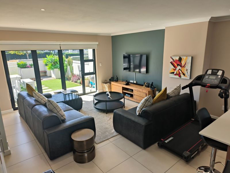A well-maintained living room featuring tiled floors, a modern accent wall, and large sliding glass doors providing direct access to the outdoor patio area.