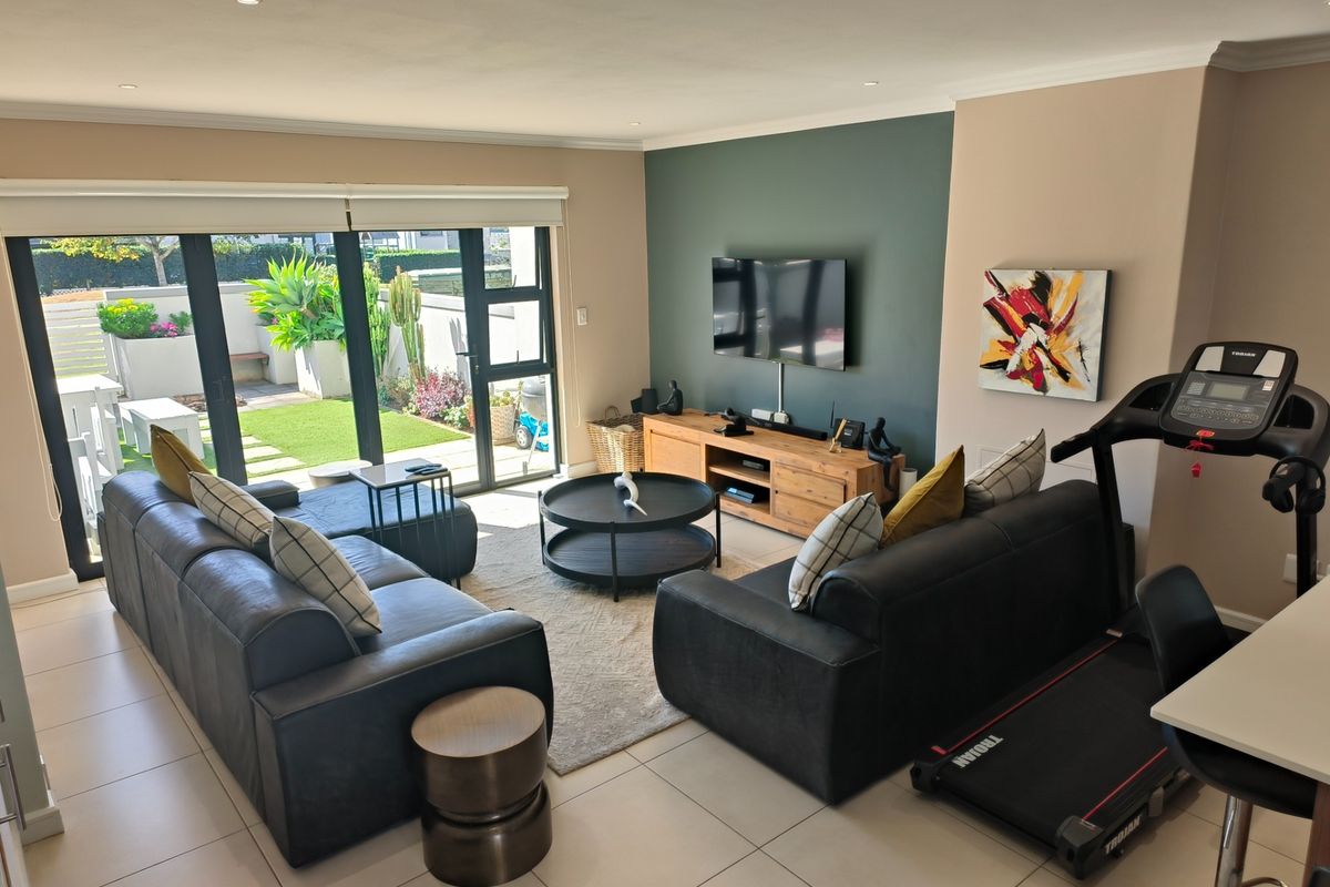 A well-maintained living room featuring tiled floors, a modern accent wall, and large sliding glass doors providing direct access to the outdoor patio area.