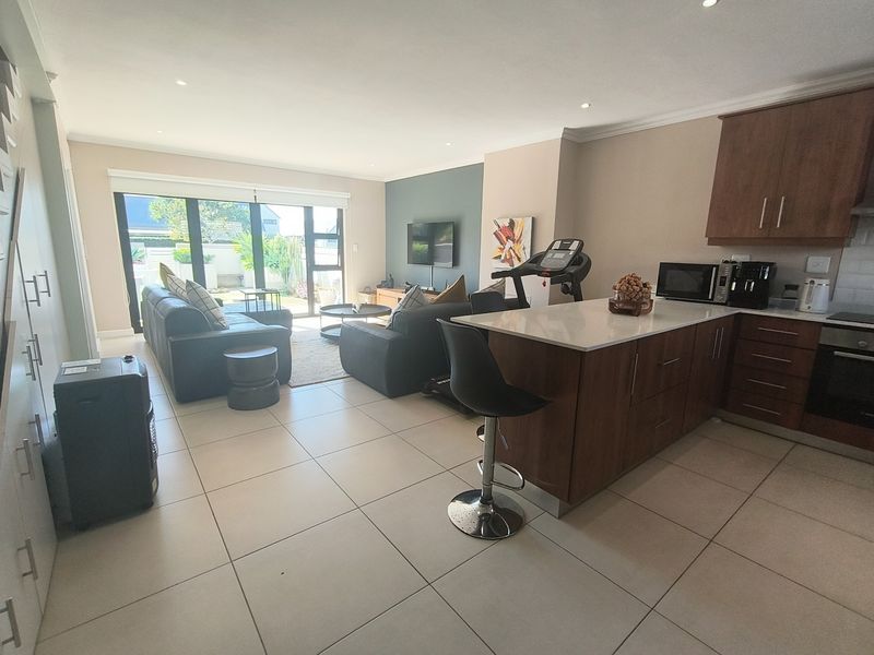 Spacious open-plan living area featuring a modern kitchen with stone countertops, tiled flooring, and large sliding doors leading to the outdoor space.