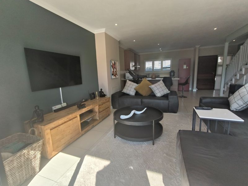 Open-plan living area featuring tiled floors, recessed lighting, and a modern kitchen with built-in cabinetry, seamlessly connected to the lounge space.