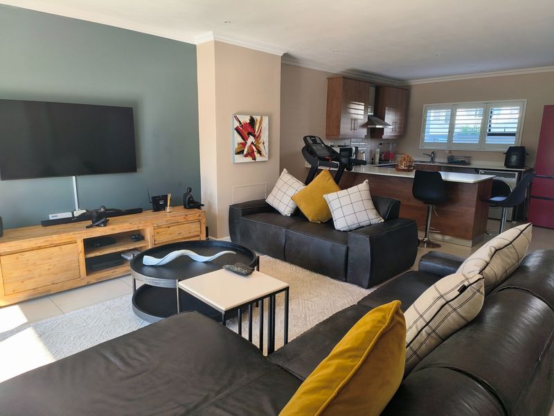 Spacious open-plan living area featuring a modern kitchen with island, tiled floors, and neutral wall tones, creating a functional and inviting home layout.