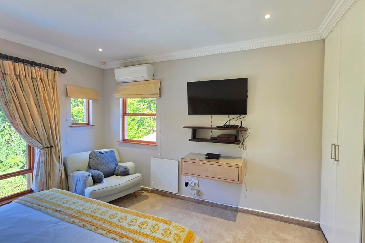 A well-maintained bedroom featuring built-in wardrobes, split-system air conditioning, and large windows with natural light.