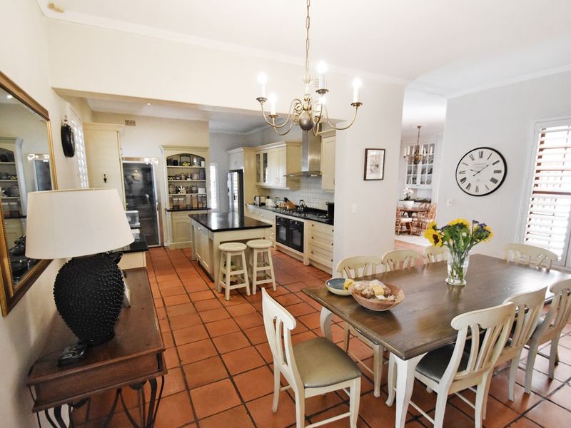 Spacious open-plan kitchen and dining area featuring terracotta flooring, classic shaker-style cabinetry, and a central island, creating a warm and functional living space.