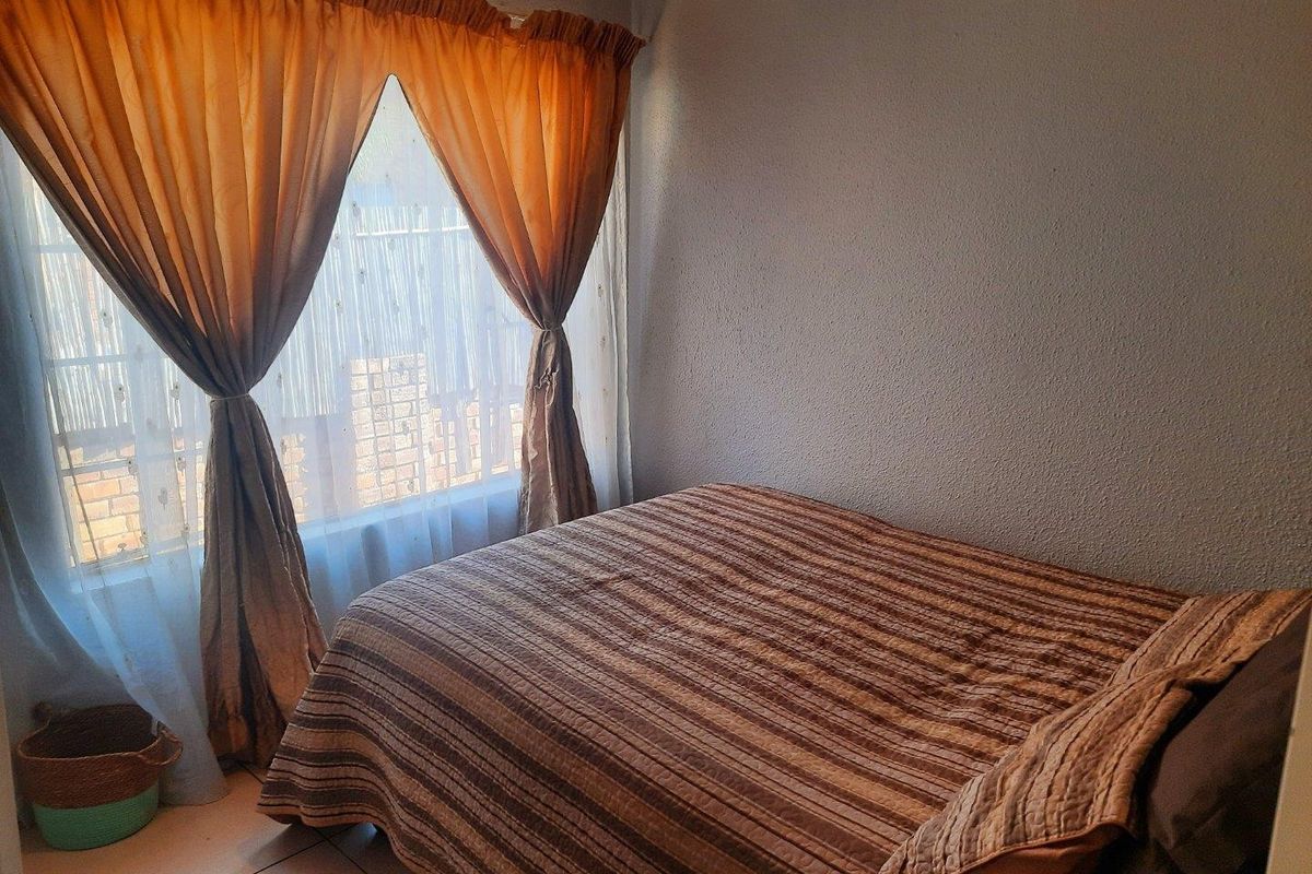 A standard bedroom featuring tiled flooring and natural light through a window with curtains.