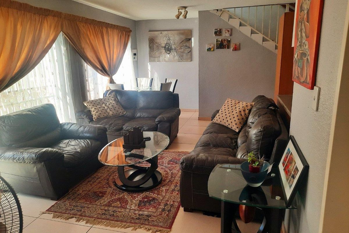 A living room area featuring tiled flooring, a staircase, and large sliding glass doors providing natural light.
