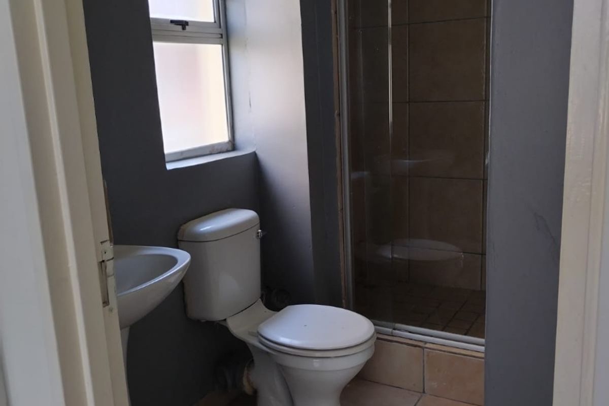 A compact bathroom featuring a pedestal basin, toilet, and a tiled shower enclosure with a glass door.