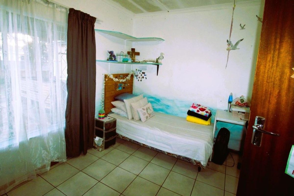 A functional bedroom featuring tiled flooring and built-in wall shelving, offering a simple and practical living space.