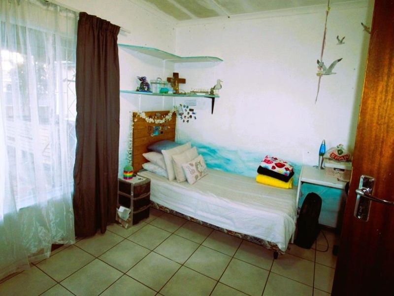 A functional bedroom featuring tiled flooring and built-in wall shelving, offering a simple and practical living space.